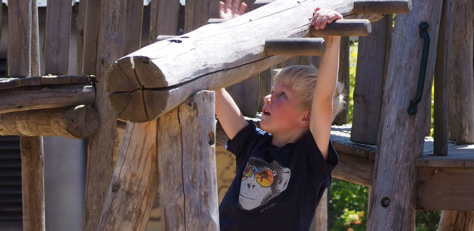 Boy swinging on pirate adventure playground